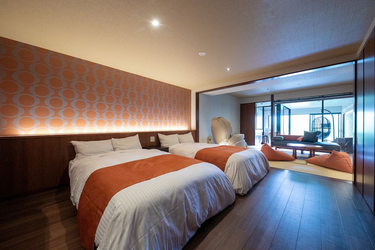 Habitación de hotel con dos camas, un sofá y zona de comedor con vistas.