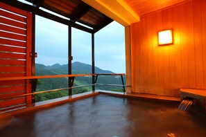 A room with a large window overlooking a mountainous landscape, a wooden interior, and a small illuminated wall feature. - Hotel Higashidate (Yamanouchi)