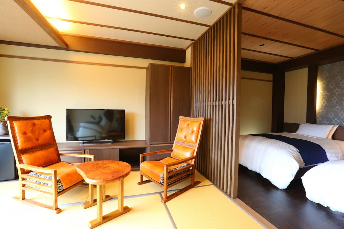 Habitación de hotel con cama, dos sillones, una mesita, televisor y puerta corredera.