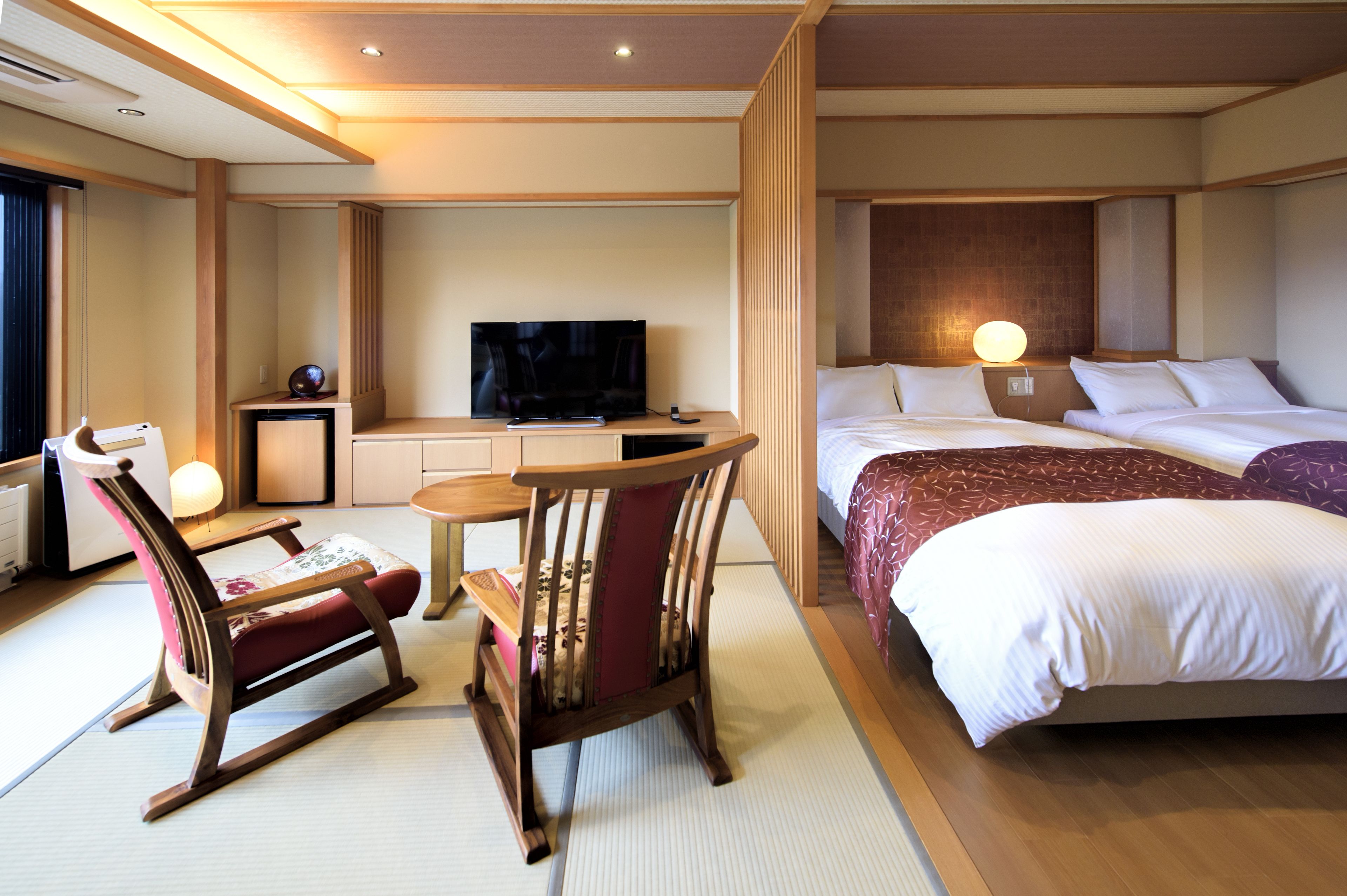 A hotel room with a bed, a TV, a desk, and a chair.