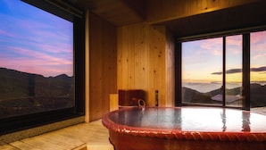 Eine Holzhütte mit Whirlpool und einem großen Fenster mit Bergblick.