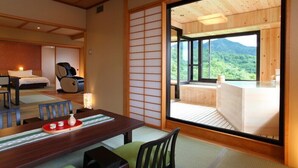 Ein traditioneller japanischer Raum mit Tatami-Bodenbelag, einem niedrigen Tisch mit Tablett und einer Schiebetür zu einem Balkon mit Bergblick.