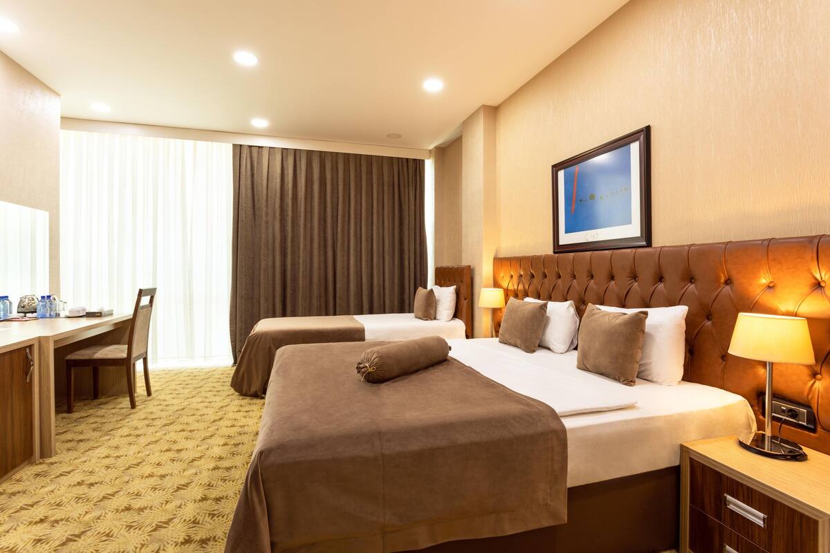 A hotel room with two beds, a desk, and a chair.
