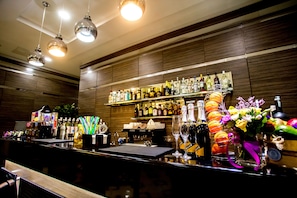 Eine Bar mit einer Auswahl an Spirituosenflaschen, einer Kaffeemaschine sowie Früchten und Blumen.