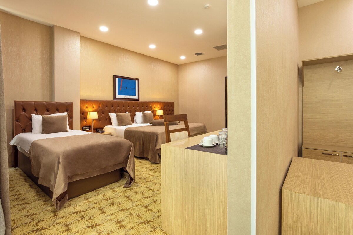 A hotel room with two beds, a desk, and a wardrobe.