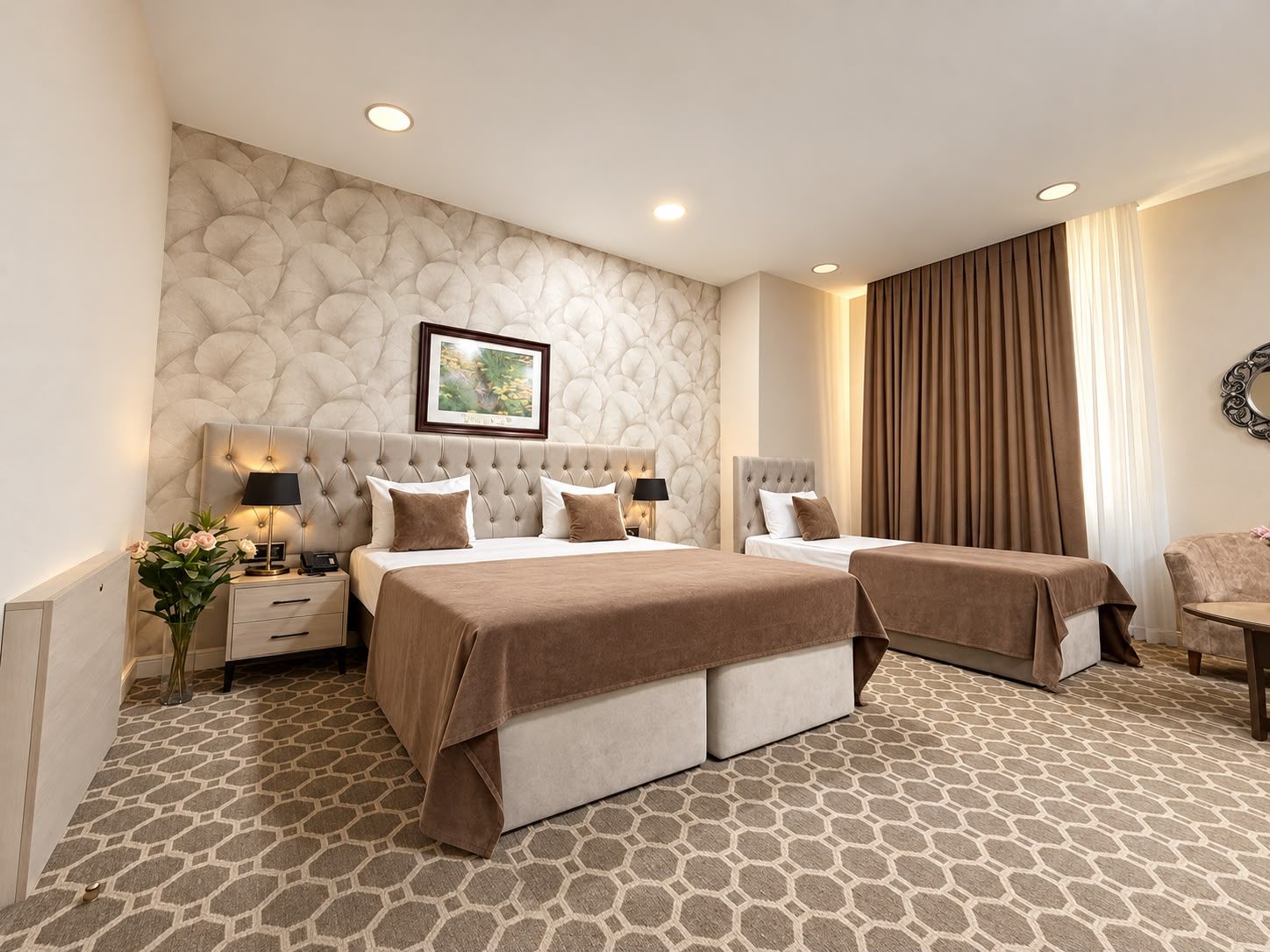 Habitación de hotel con una cama grande, una cama individual, una mesita de noche con lámpara, un aparador y un cuadro colgado en la pared.