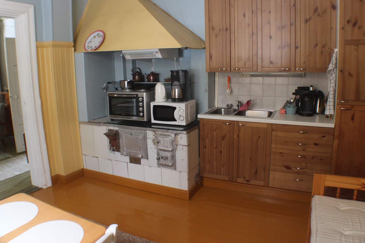 A compact kitchen with wooden cabinets, a microwave, a toaster, and a sink.