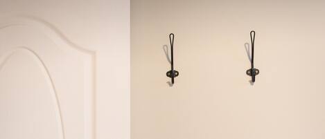 A white door with a brass doorknob and two wall-mounted hooks.
