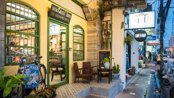 Un hostal con un marco de ventana verde, una bicicleta afuera y un letrero para un café y bar.
