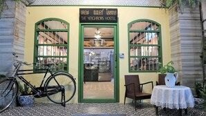 A hostel with a green door and windows, a bicycle outside, and a table with a pitcher. - The Neighbors Hostel - Adults Only (Phuket)