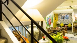 A staircase leading to a dining area with a table, chairs, and a vase with flowers. - The Neighbors Hostel - Adults Only (Phuket)