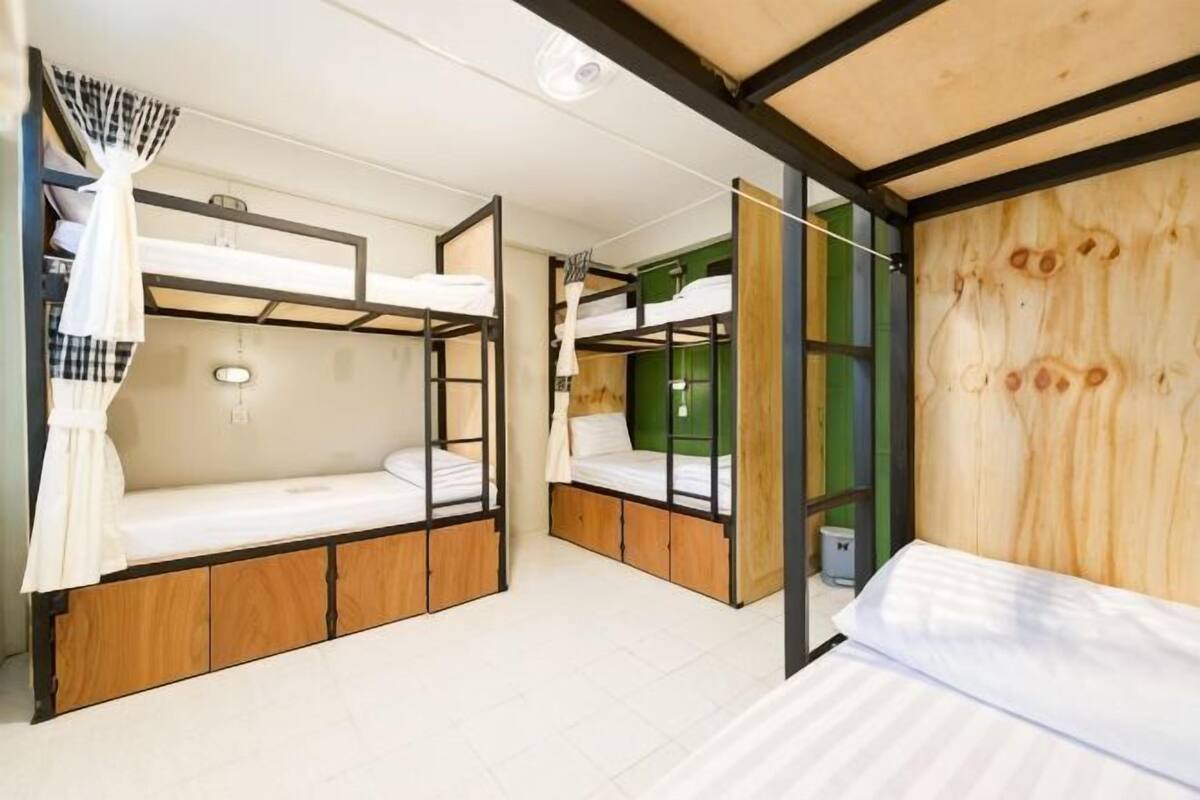 A room with bunk beds, a wooden wall, and a window.