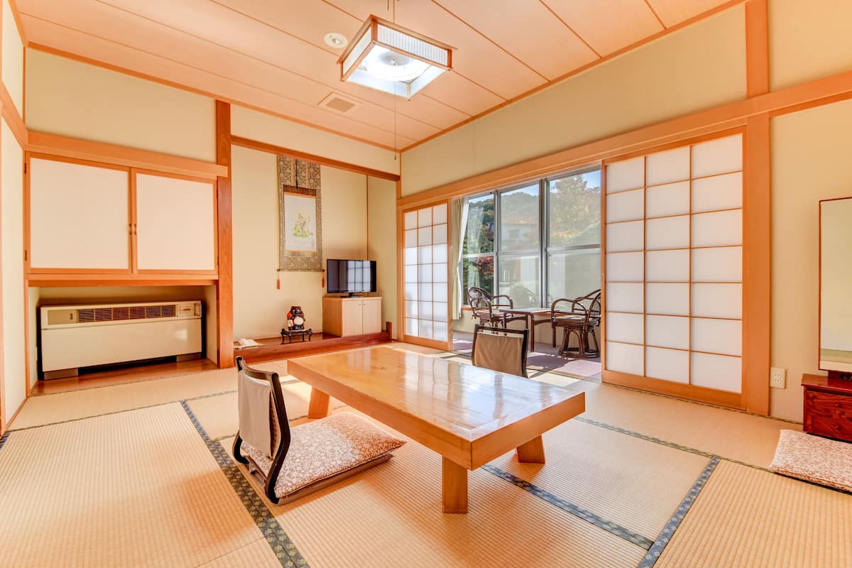 Habitació japonesa tradicional amb sòcols de tatami, una taula de fusta, portes corredisses i una televisió.