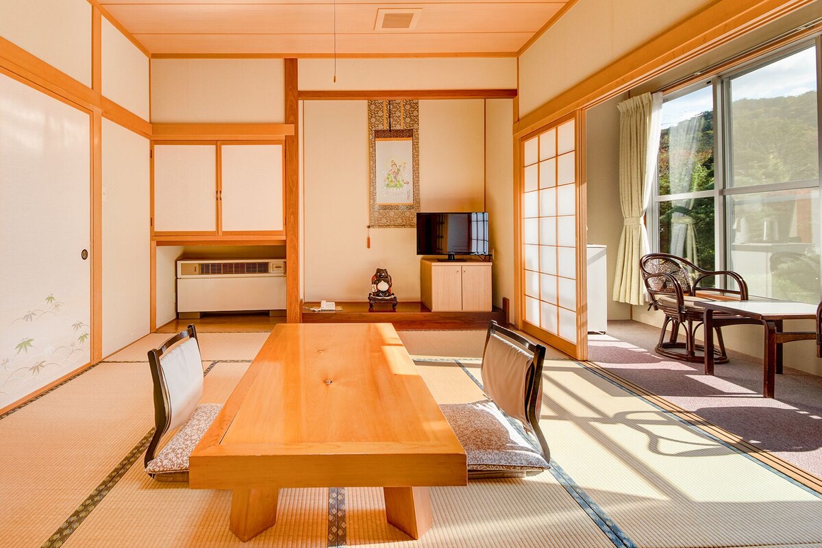 A traditional Japanese-style room with tatami flooring, a wooden dining table, and sliding doors.