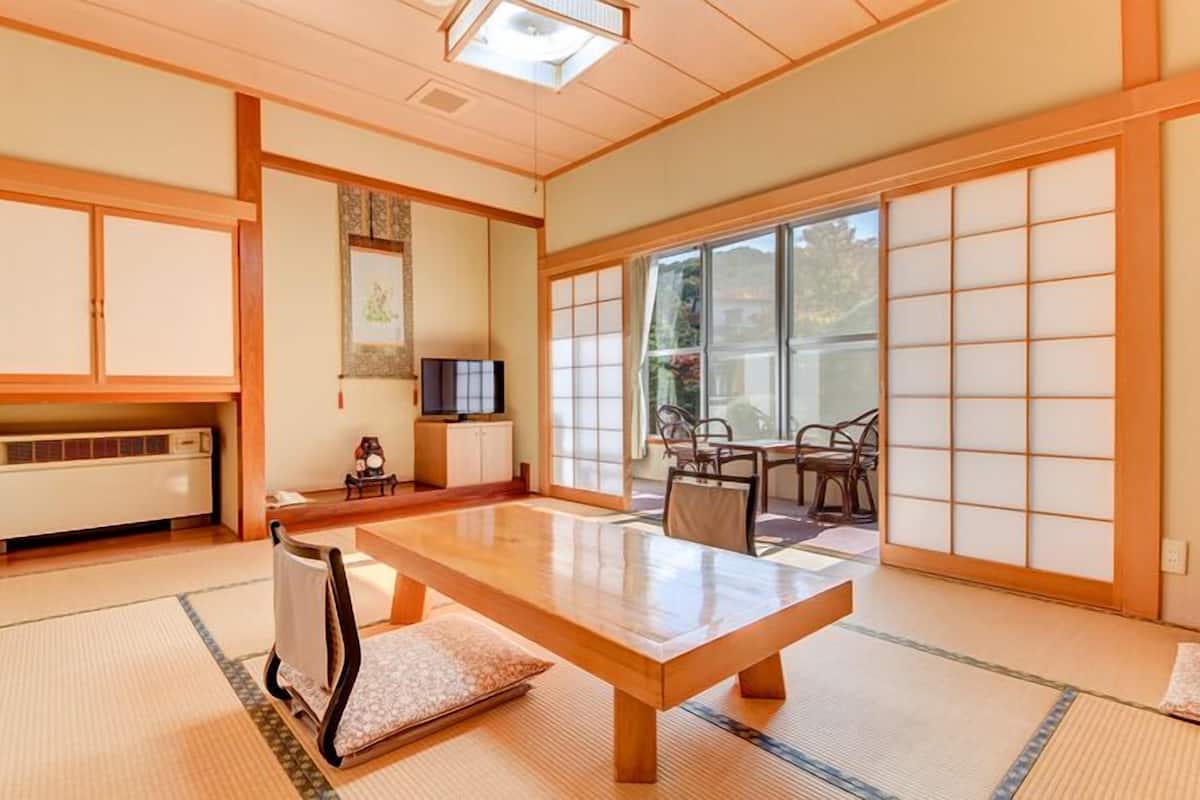 Perinteinen japanilaistyylinen huone, jossa on tatamimatto, matala puupöytä, liukuovet ja televisio.