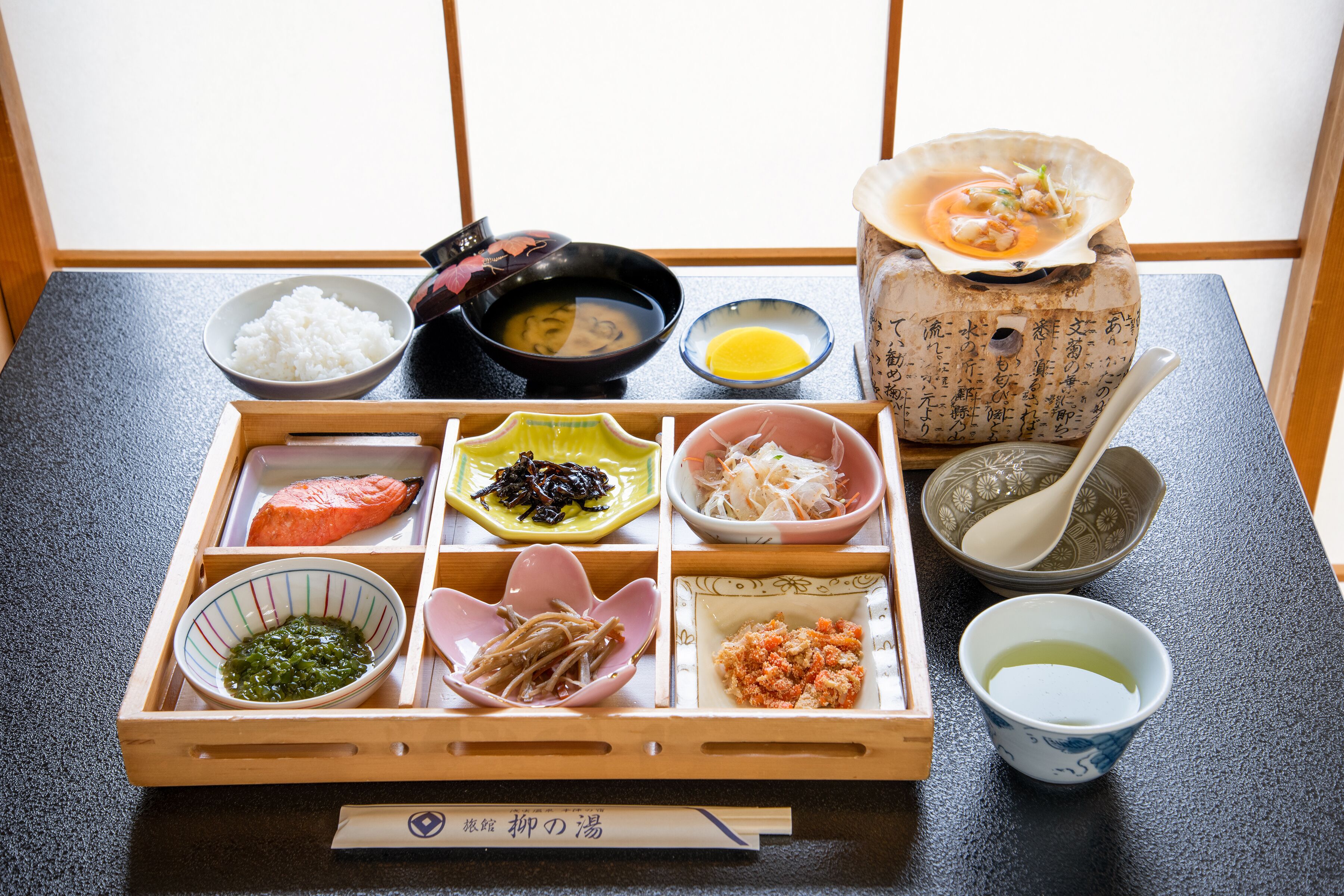Een traditionele Japanse bento-box met verschillende soorten eten en een kleine kom soep.