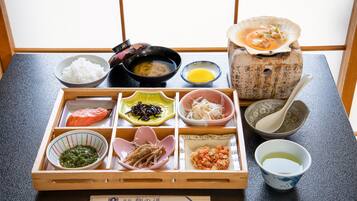 Een traditionele Japanse bento-box met verschillende soorten eten en een kleine kom soep.