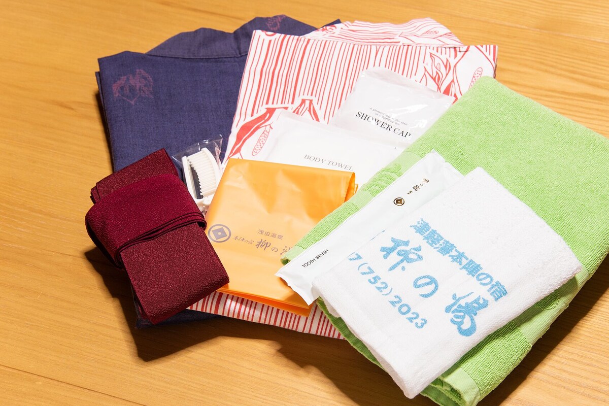 A variety of personal care items including a red towel, a green towel, a white towel, a body towel, a shower cap, and a toothbrush.