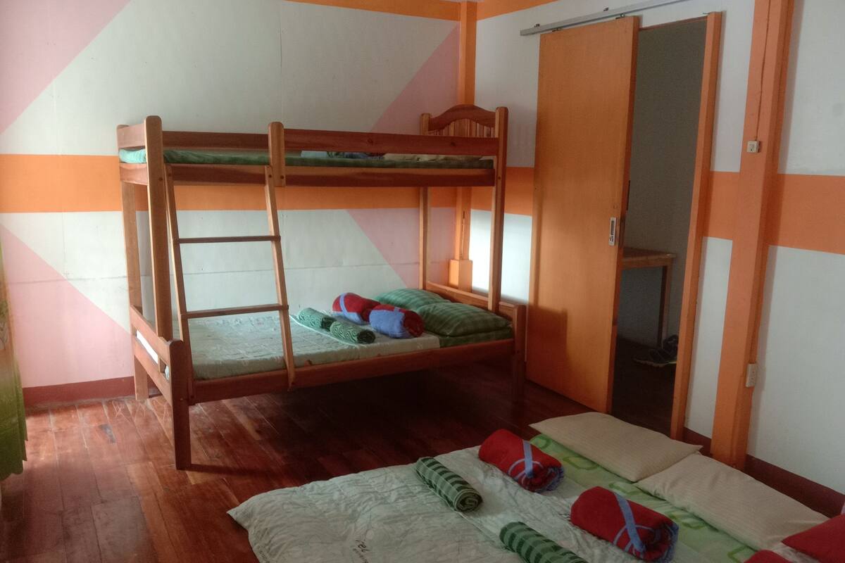 Una cama individual con almohadas, una litera y un armario.