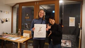 Two people holding a sign for Tomaritg Hostel.