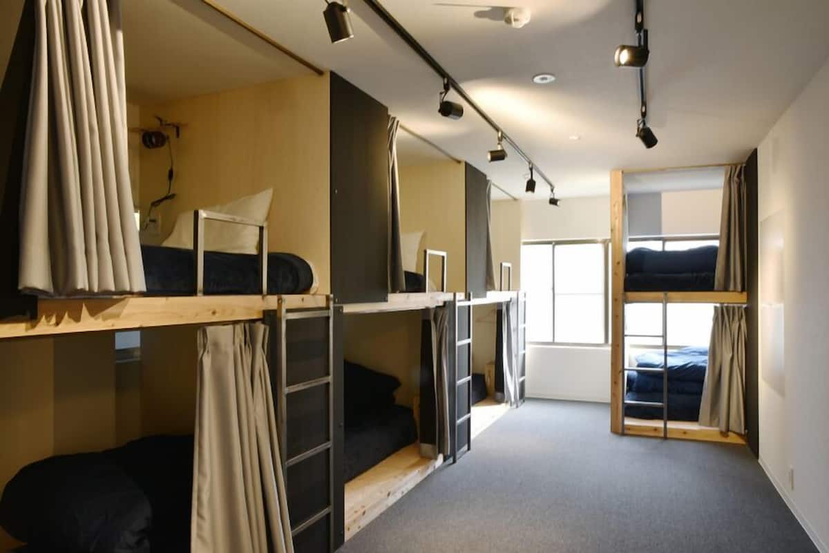 A dormitory room with bunk beds, a window, and a door.