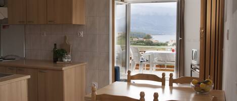 Una cocina con armarios de madera, una mesa de comedor con sillas y vistas al exterior a través de un ventanal.