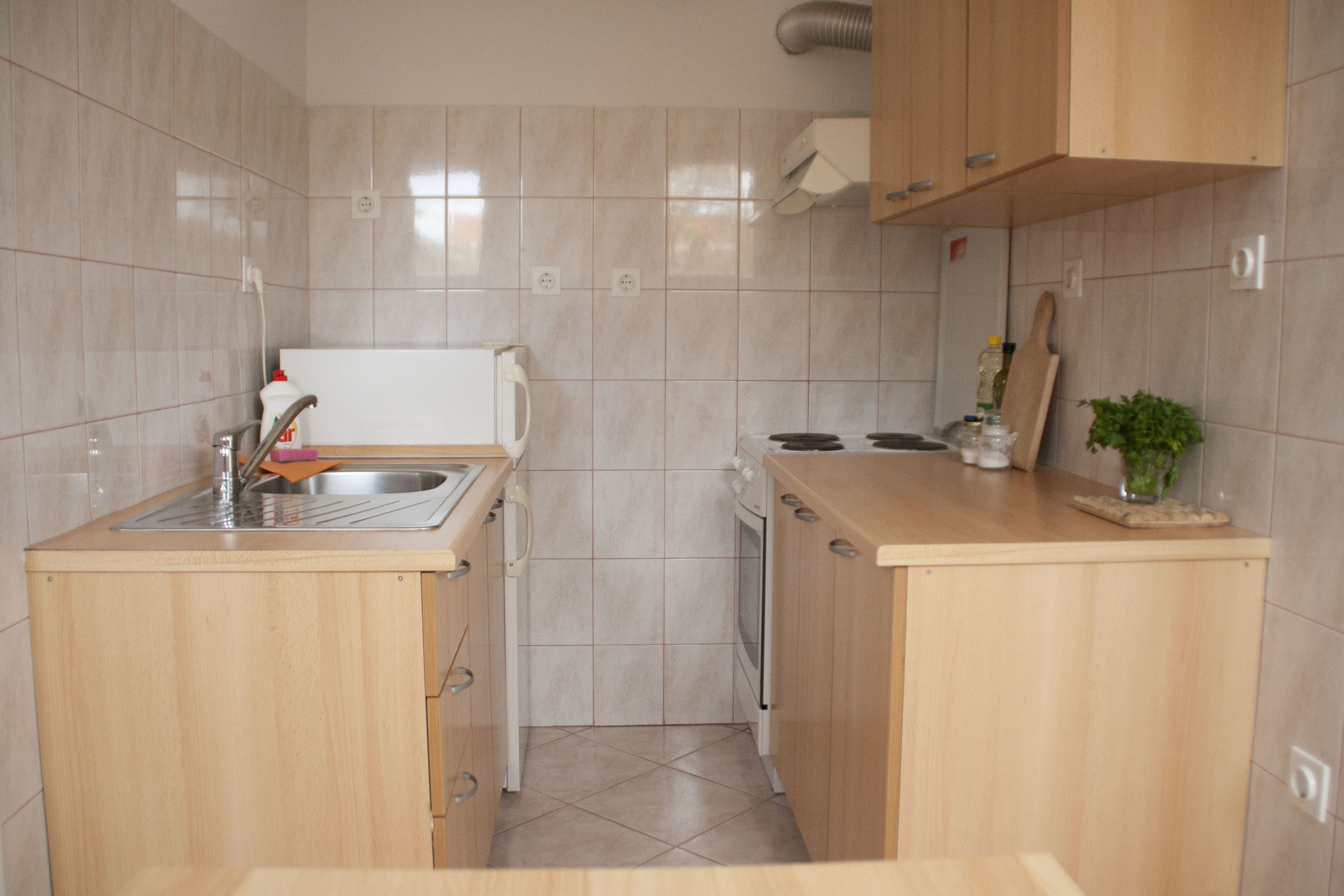 A compact kitchen with a sink, dishwasher, and wooden cabinets.