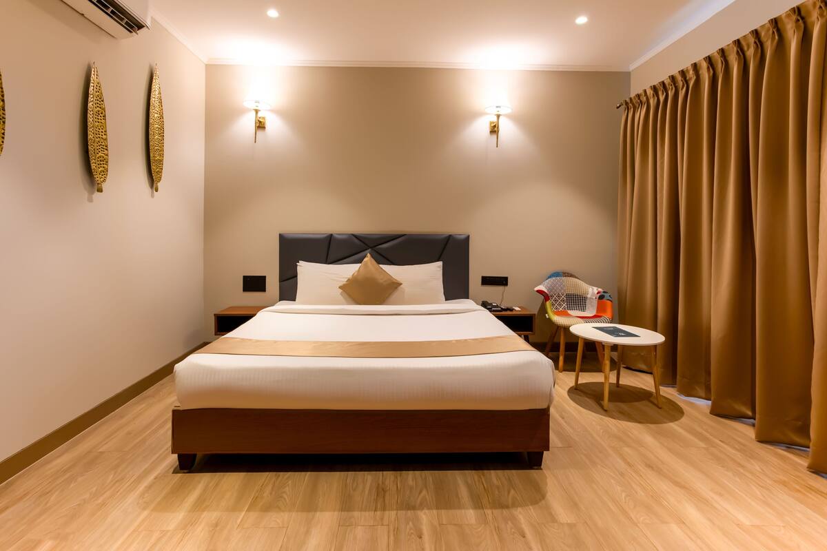 A hotel room with a large bed, bedside tables, a chair, and a small table.