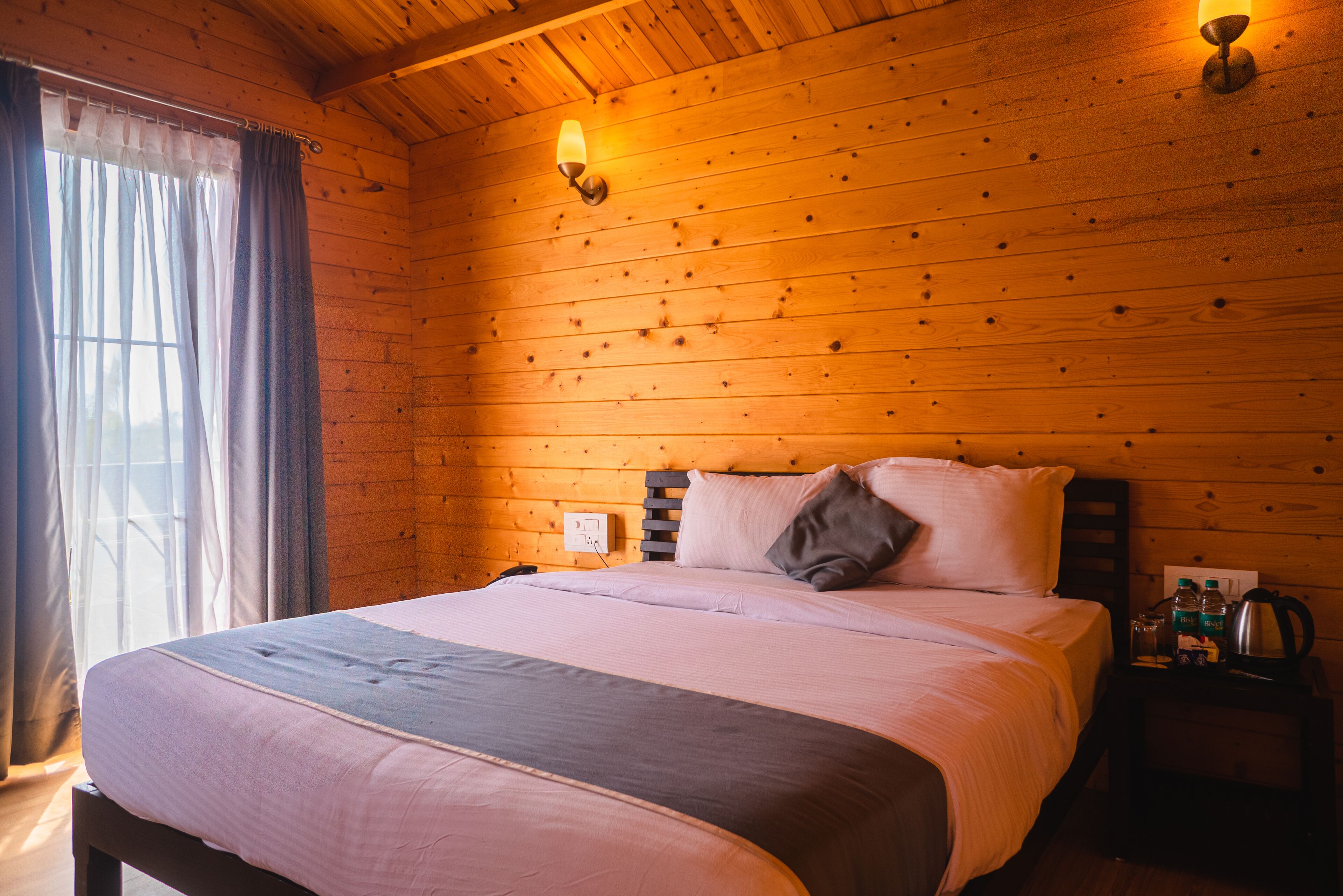 A wooden-paneled room with a bed, a nightstand, and a lamp.
