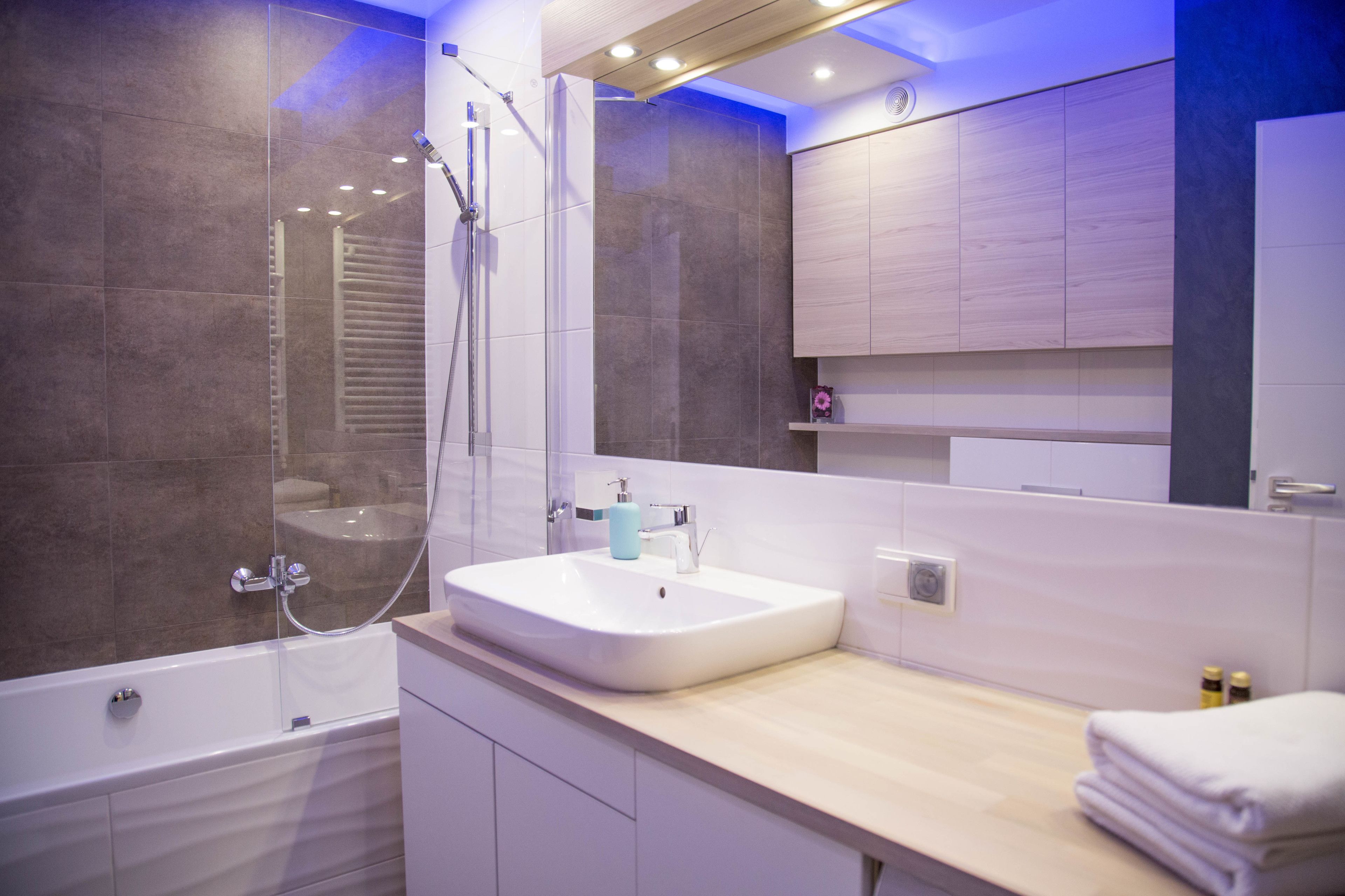 A modern bathroom with a bathtub, shower, and sink.