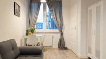 Un salón moderno con un sofá gris, una mesita con un florero y una ventana con cortinas.