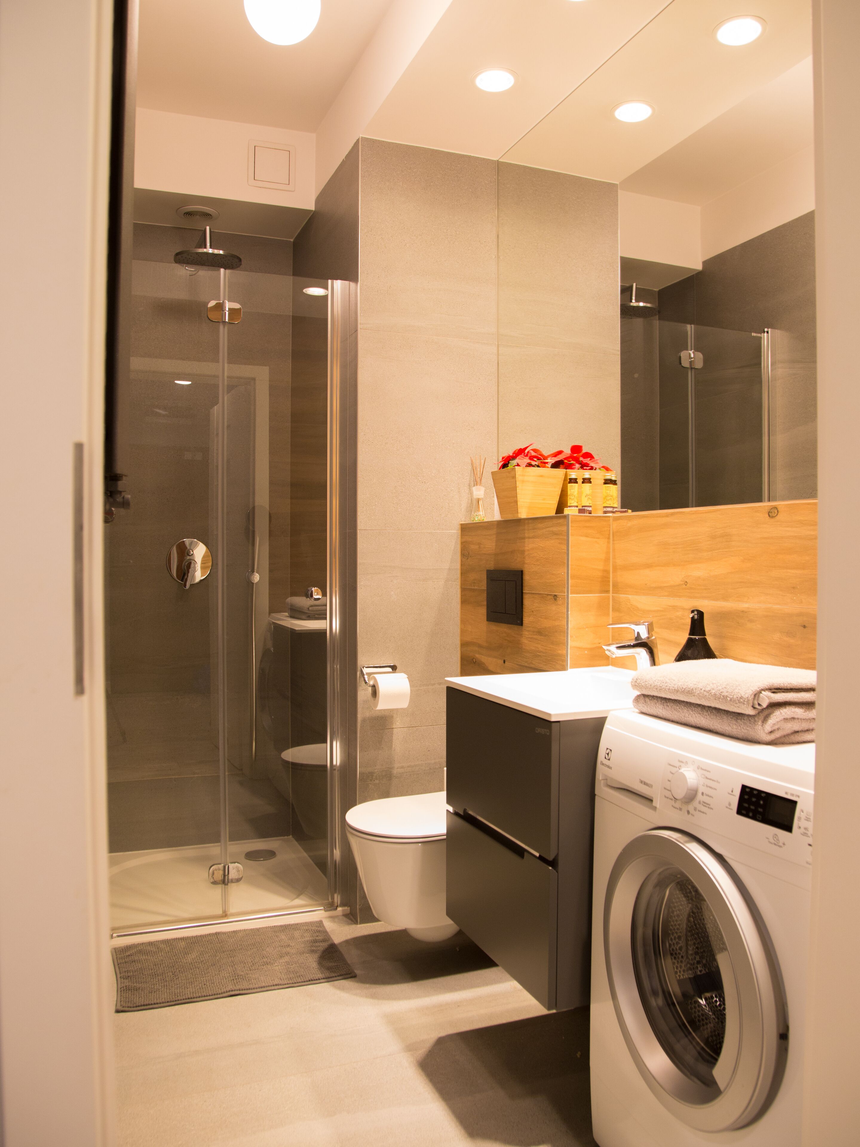 A modern bathroom with a glass-enclosed shower, a toilet, a sink, and a washing machine.