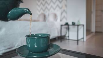 A green teapot pouring tea into a matching teacup on a table.