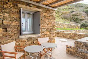 A stone building with a window, two round tables, and wooden chairs.