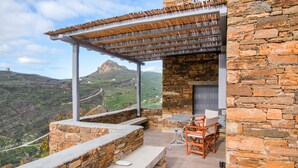 A stone building with a wooden pergola and a table with chairs. - Tinos Pegion House (Tinos)