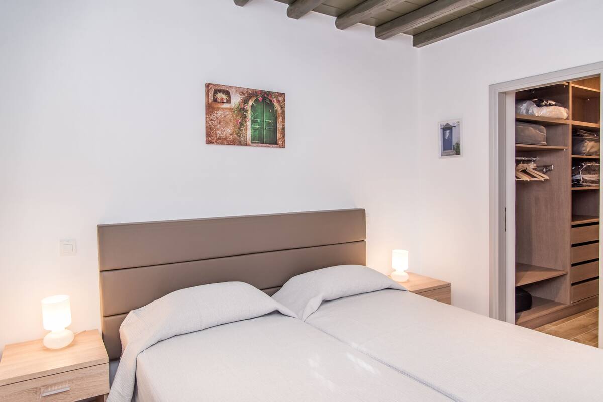 Une chambre à coucher avec un lit, des lampes de chevet, une armoire et un tableau au mur.