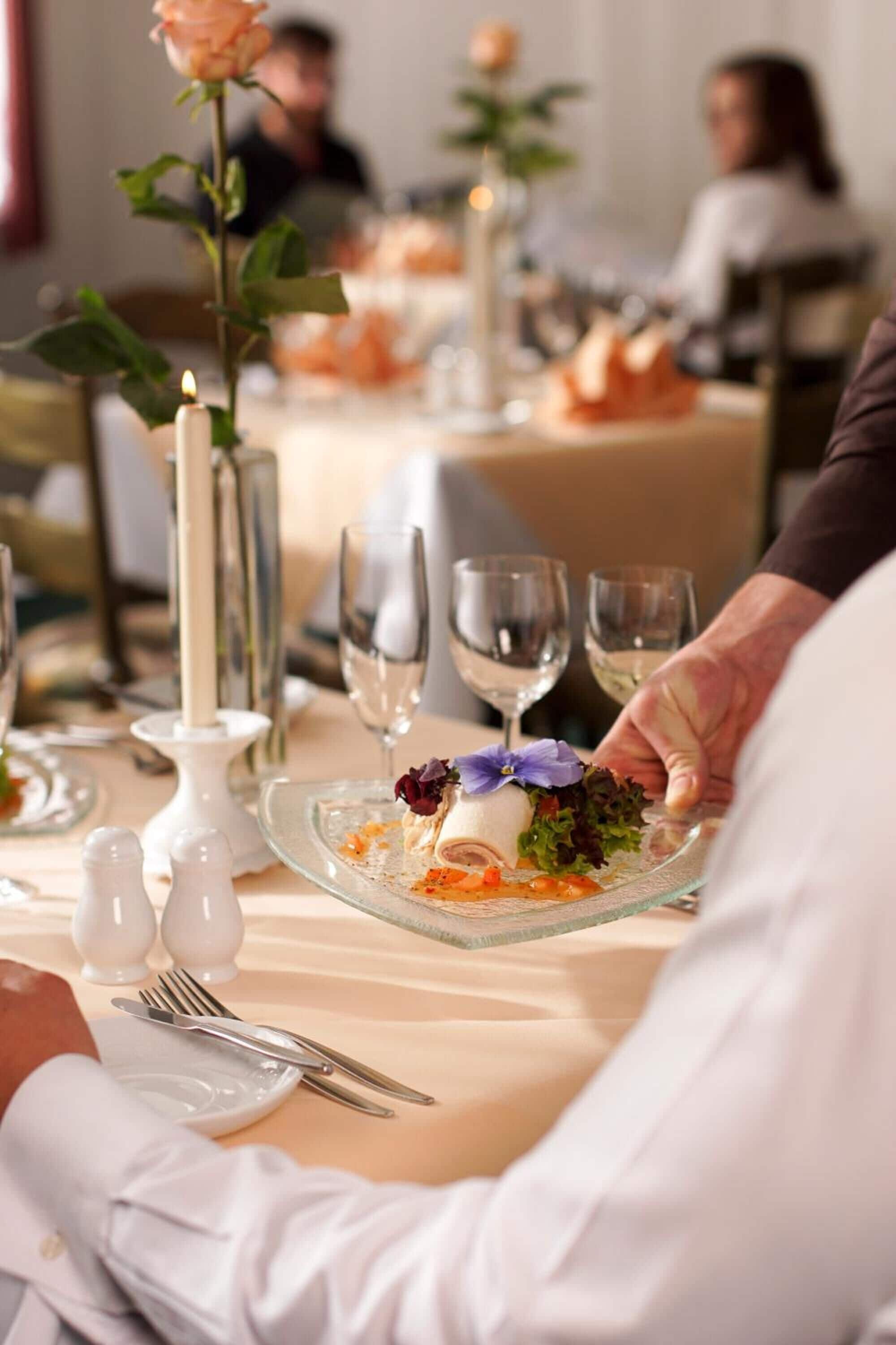 A dining table set with plates, cutlery, and a candle.
