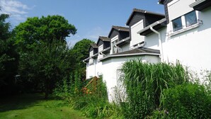 A modern multi-story house with a white exterior, multiple balconies, and a well-maintained garden. - Das Fritz Hotel (Schwerin)