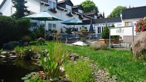A hotel courtyard with outdoor seating, a fountain, and a pond. - Das Fritz Hotel (Schwerin)
