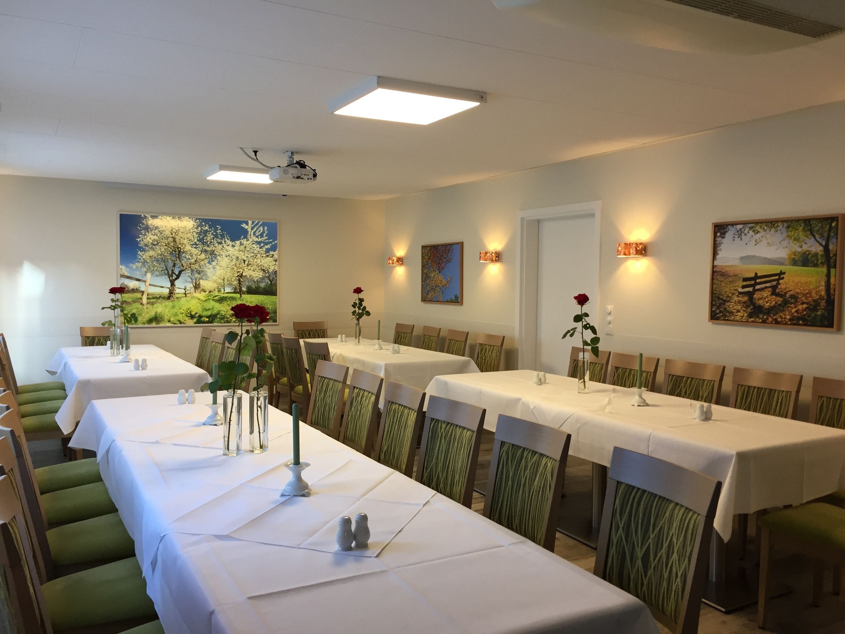 A dining area with long tables, chairs, and artwork on the walls.