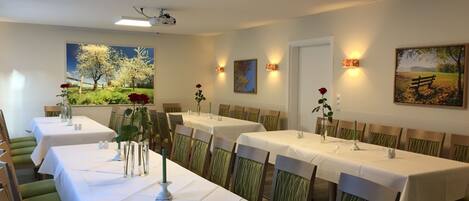 A dining area with long tables, chairs, and artwork on the walls.