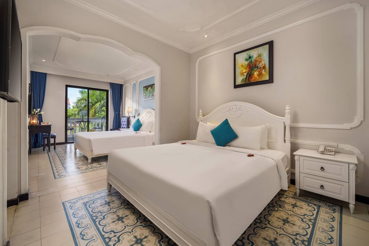 A hotel room with two beds, a desk, and a chair.