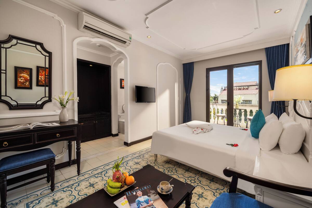 A hotel room with a bed, a desk, a chair, a TV, and a window with a view.