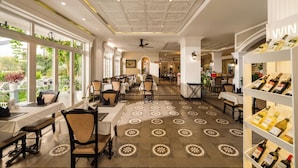 A restaurant with a long counter, chairs, and a wine rack. - Hoi An Rosemary Boutique Hotel & Spa (Da Nang)