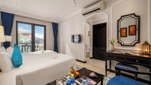 A hotel room with a bed, a desk, a chair, a coffee table, and a TV. - Hoi An Rosemary Boutique Hotel & Spa (Da Nang)