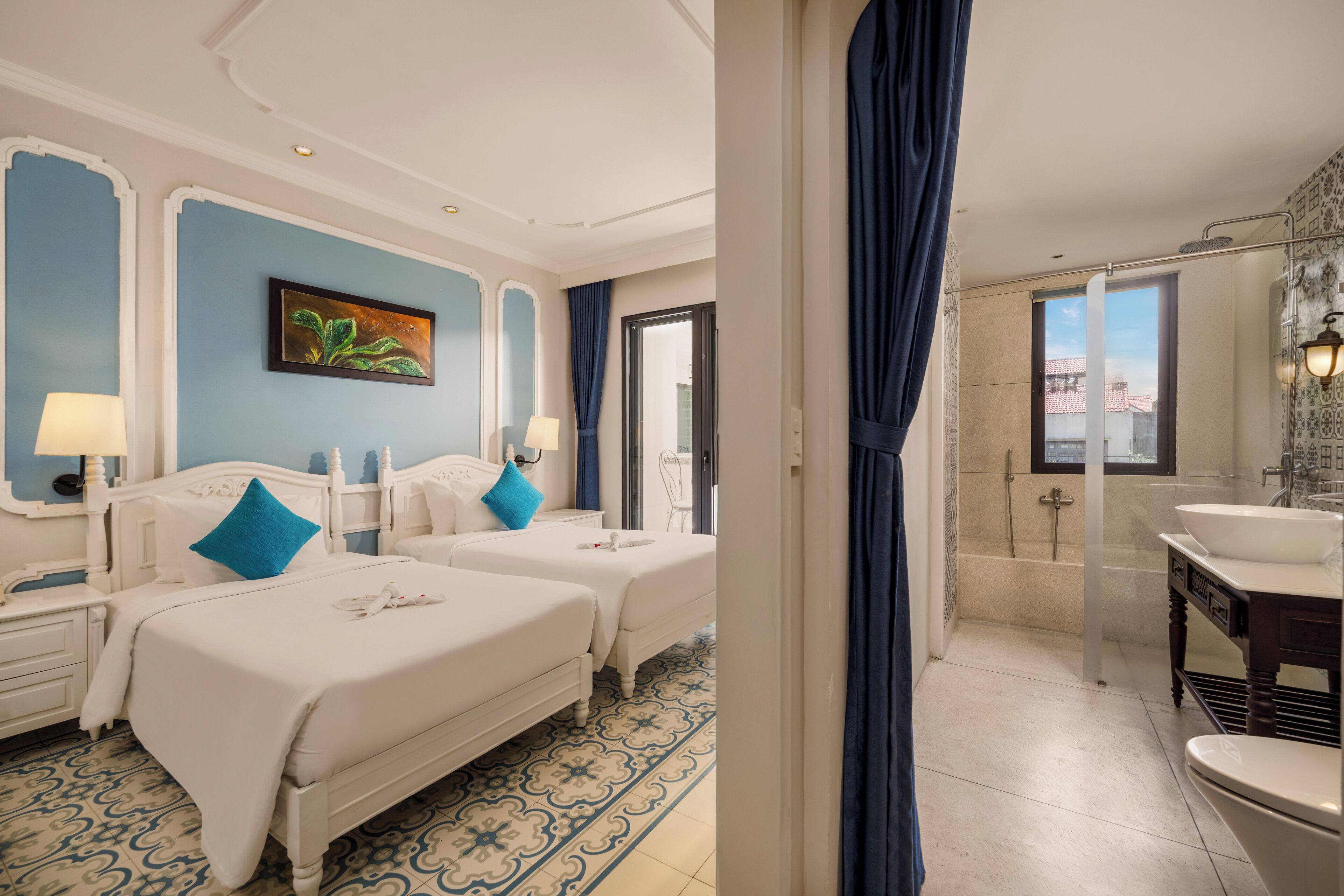 Een hotelkamer met twee bedden, een badkamer met bad en uitzicht op de stad.