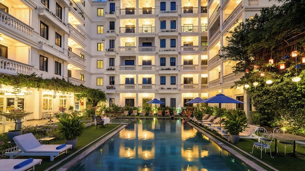 A hotel with a central pool, multiple balconies, and outdoor seating areas. - Hoi An Rosemary Boutique Hotel & Spa (Da Nang)