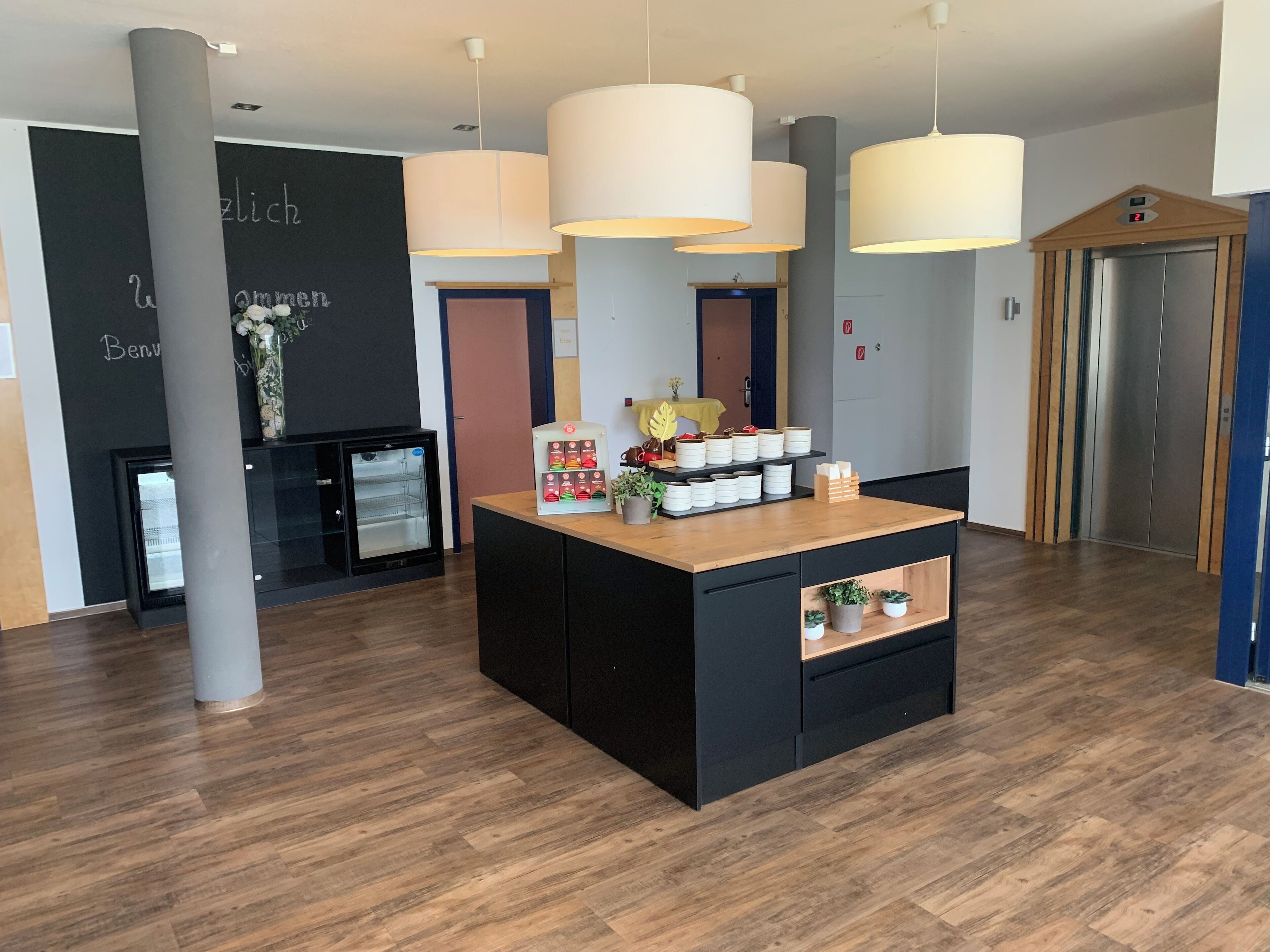A reception area with a wooden reception desk, a refrigerator, and a wall with text.