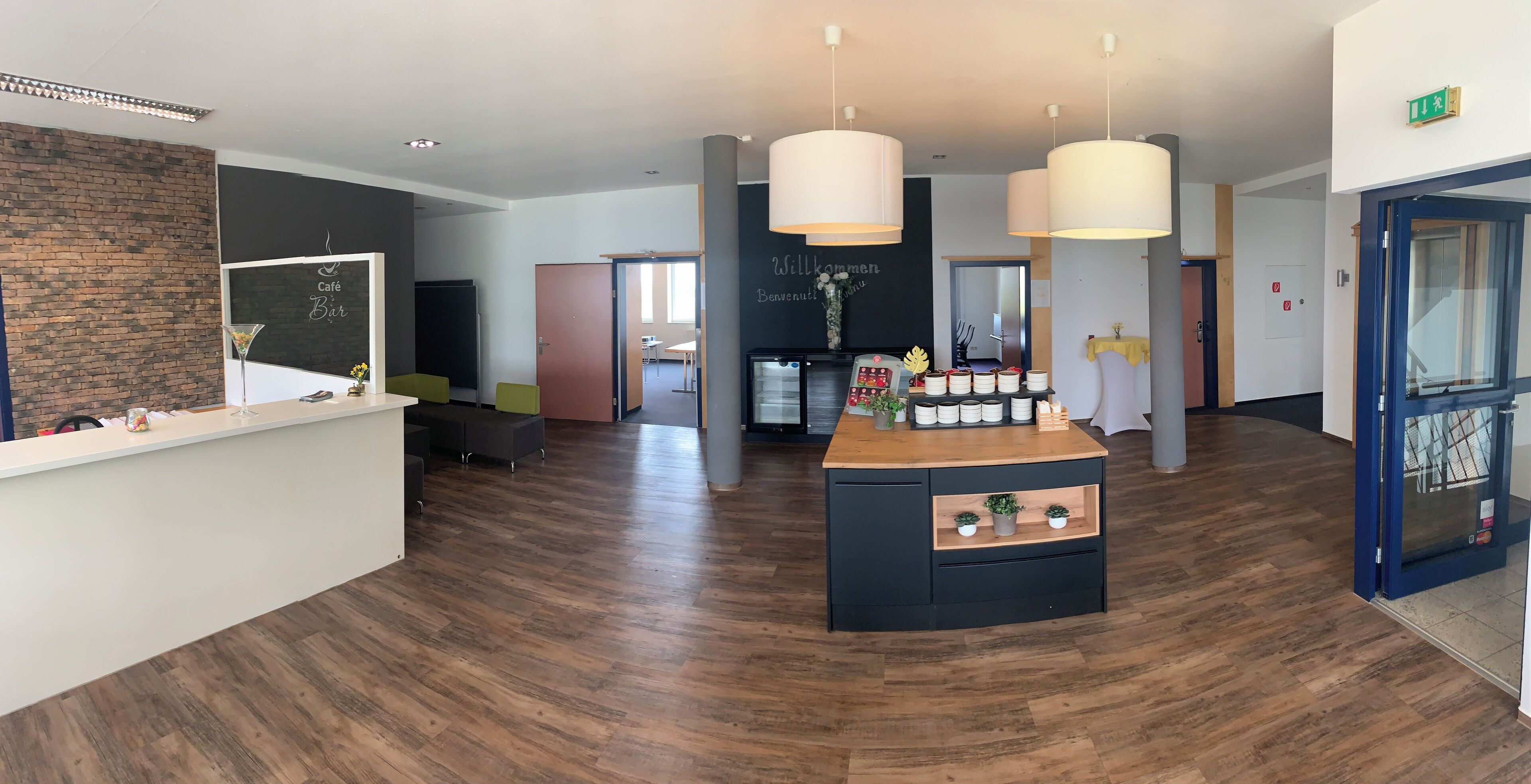 A modern hotel lobby with a reception desk, seating area, and a bar.
