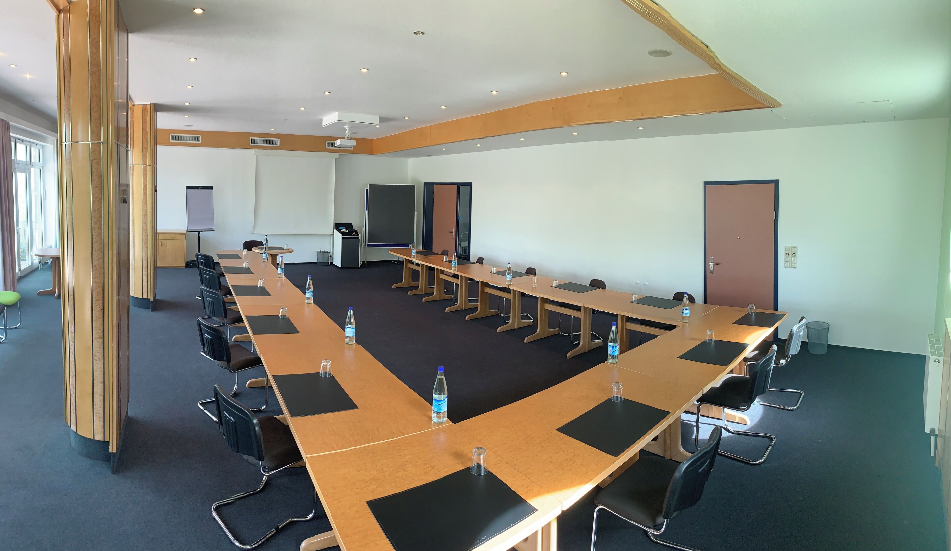 A conference room with long tables, chairs, and water bottles.